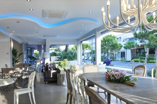 Moderní interiér restaurace s velkými okny a stropním osvětlením.