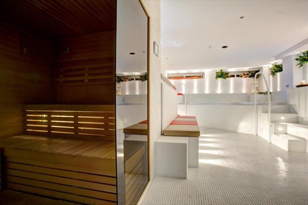 Moderní wellness prostor s dřevěnou saunou a bílými keramickými prvky.