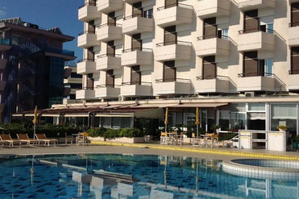 Hotel s balkony a bazénem v popředí.