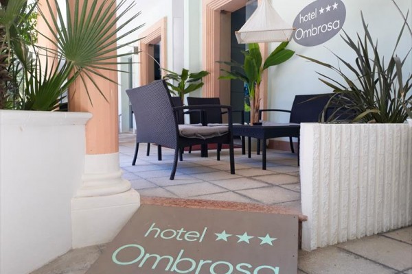 Zahradní posezení u hotelu Ombrosa s ratanovými židlemi a kytkami.
