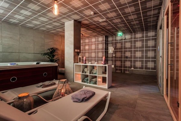 Wellness místnost s lehátky, vířivkou a saunou v moderním stylu.  