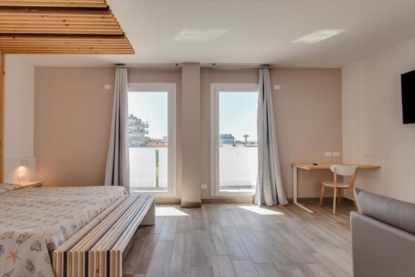 Moderní hotelový pokoj s velkými okny a výhledem na město.  