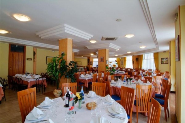 Elegantně prostřená restaurace s kulatými stoly a dřevěnými židlemi.