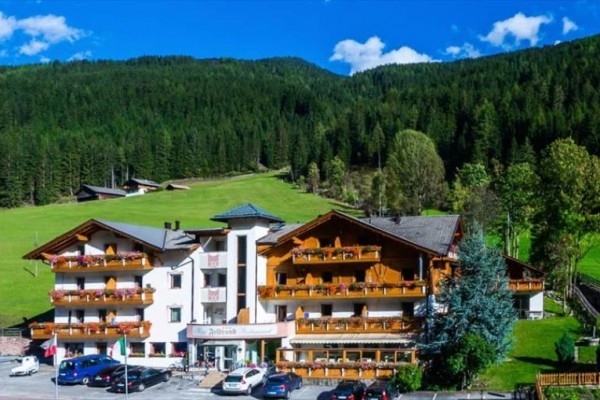 Hotel v horské krajině obklopený lesy a loukami.