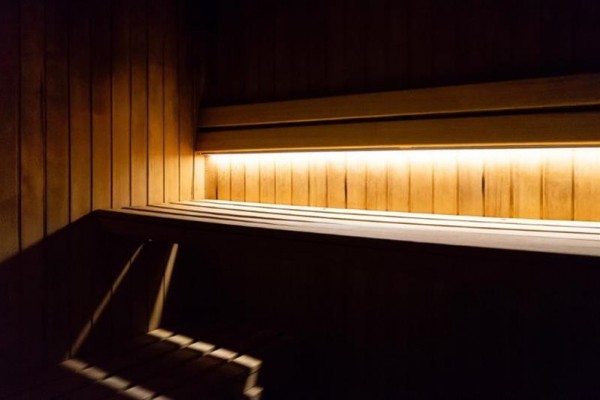 Dřevěný interiér sauny osvětlený teplým světlem.  