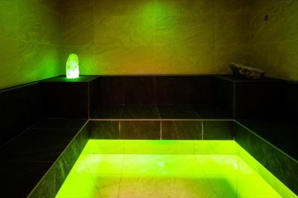 Parní lázeň s černými lavicemi a zeleným osvětlením.