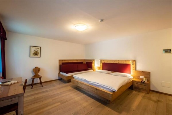 Hotelový pokoj s manželskou postelí, pohovkou a dřevěným nábytkem.