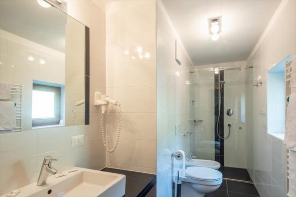 Moderní koupelna s umyvadlem, toaletou a proskleným sprchovým koutem.