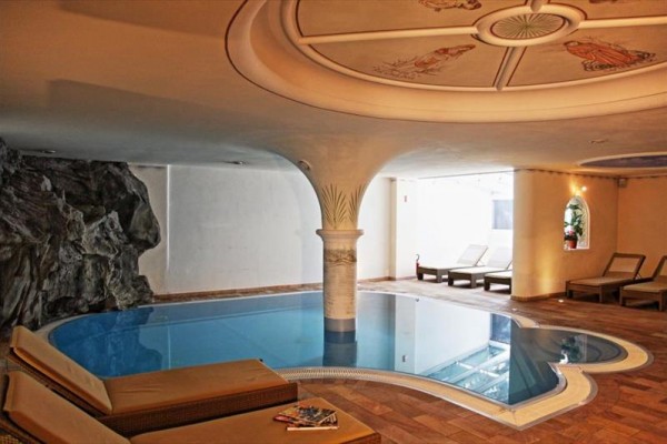 Vnitřní bazén s lehátky a dekorativním stropem.