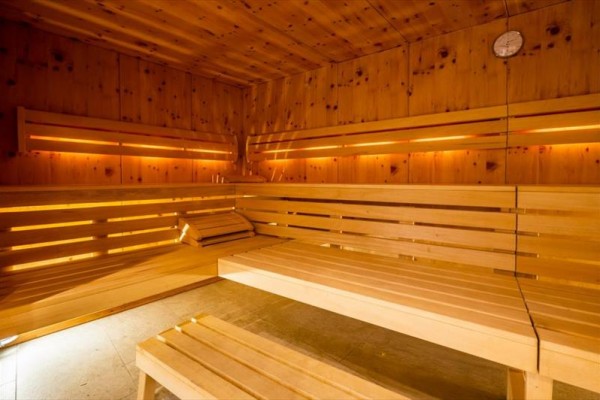 Interiér dřevěné sauny s lavicemi a jemným osvětlením.  