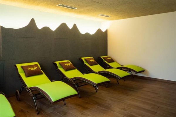 Řada zelených lehátek s hnědými polštáři v moderním relaxačním prostoru.