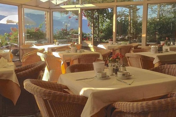 Prostorná restaurace s proutěnými židlemi a výhledem na hory.