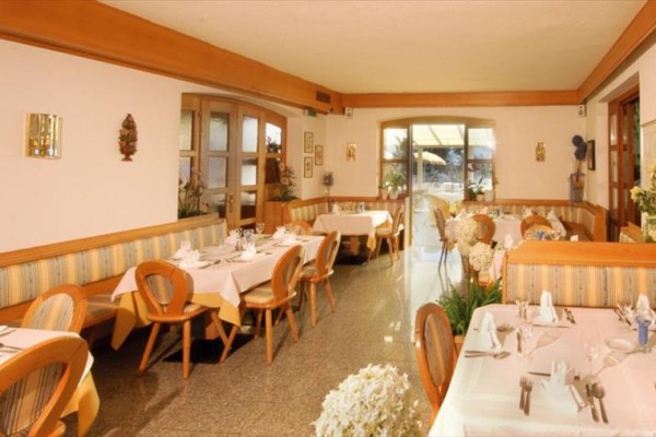 Uvnitř restaurace s dřevěnými židlemi a stoly prostřenými bílými ubrusy.