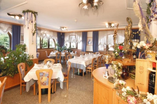 Restaurace s dřevěnými stoly, židlemi a dekoracemi, s ubrusy a květinami.