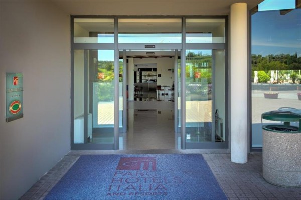 Vstup do hotelu s automatickými dveřmi a rohožkou s logem.