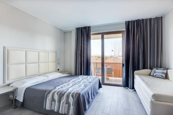 Moderní ložnice s manželskou postelí a balkonem.