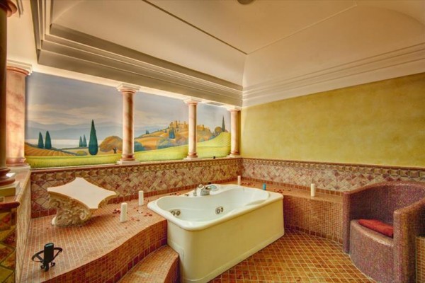 Luxusní koupelna s vířivkou a malbou toskánské krajiny na zdi.