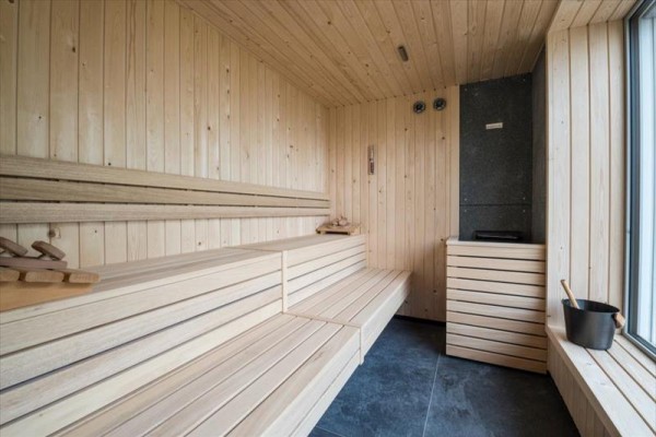 Dřevěná sauna s lavicemi a kamny.