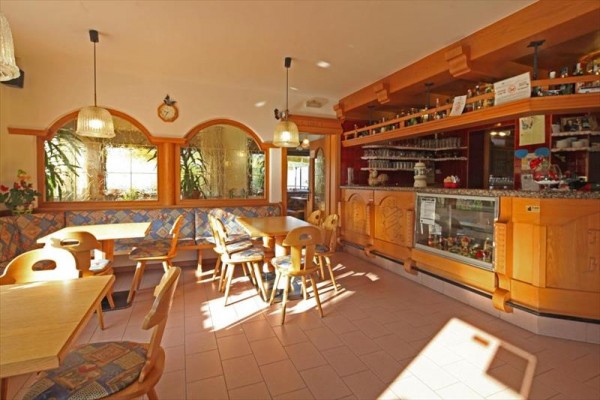 Světlá restaurace s dřevěným nábytkem a barem.