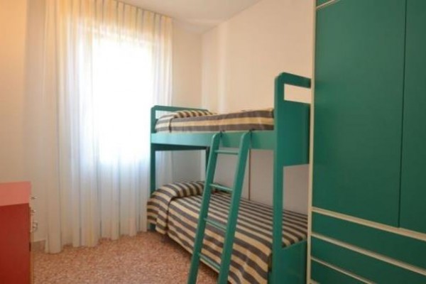 Pokoj s palandou, zelenou skříní a červenou komodou u okna.