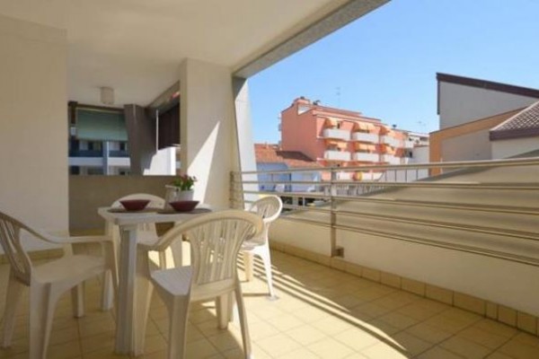 Balkon s plastovým stolem a židlemi s výhledem na budovy.