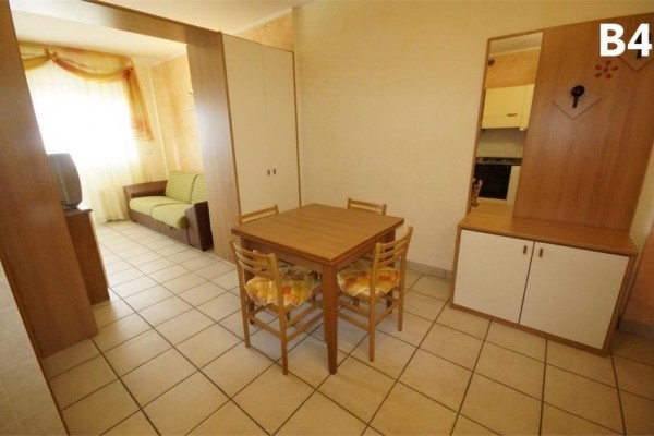 Obývací pokoj s jídelním stolem, židlemi, pohovkou, televizí a skříní.