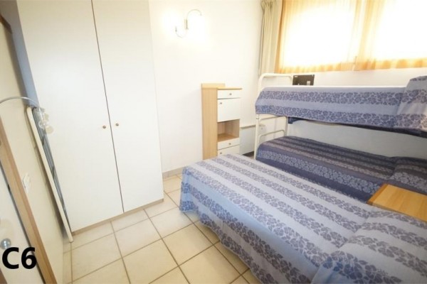 Pokoj s palandou, jednolůžkem, vestavěnou skříní a komodou.