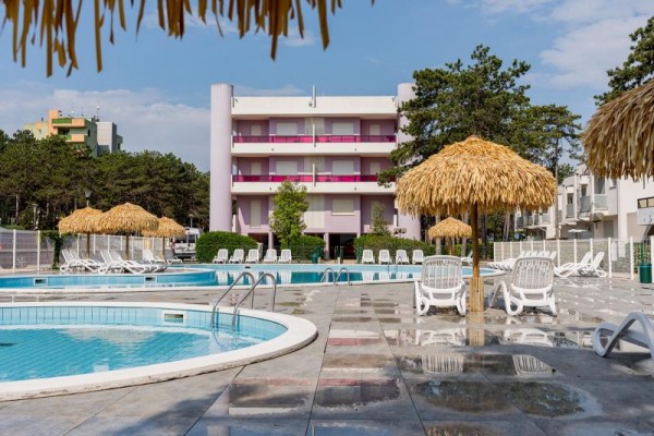 Bazén u hotelu obklopený lehátky a slunečníky.