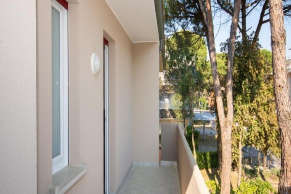Úzký balkon s výhledem na stromy a ulici.