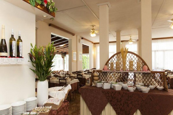 Hotelová restaurace s připraveným bufetem a ozdobami na stolech.