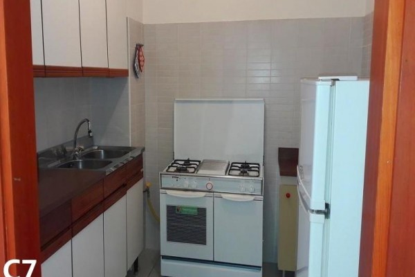 Malá kuchyně s plynovým sporákem, dřezem a ledničkou.  