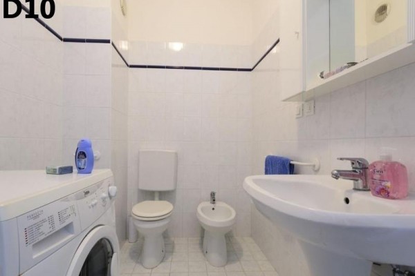 Koupelna s pračkou, toaletou, bidetem, umyvadlem a zrcadlovou skříňkou.